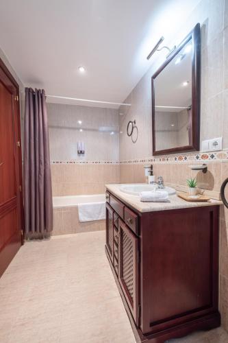 a bathroom with a sink and a mirror and a tub at Apartamento céntrico Rincón de Ensueño Parking gratis in Jaén