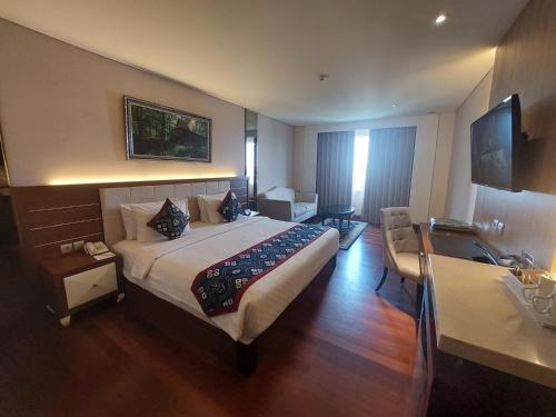 Habitación de hotel con cama grande y escritorio. en Grand Qin Hotel Banjarbaru, en Banjarbaru