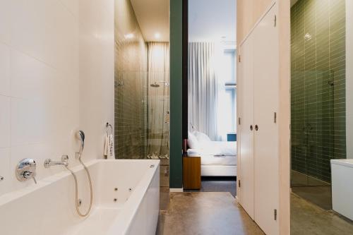 La salle de bains est pourvue d'une baignoire, d'une douche et d'un lavabo. dans l'établissement Hotel De Hallen, à Amsterdam