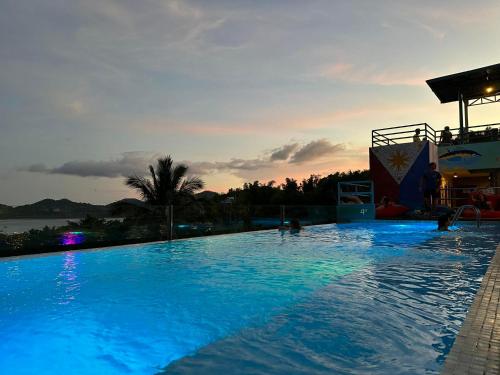 a large swimming pool with a sunset in the background at Outpost Hostel - Coron in Coron