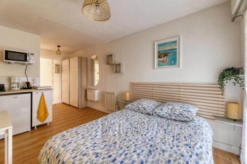 a bedroom with a bed and a kitchen at Charmant studio à 5 minutes de la mer à pied in Saint-Nazaire