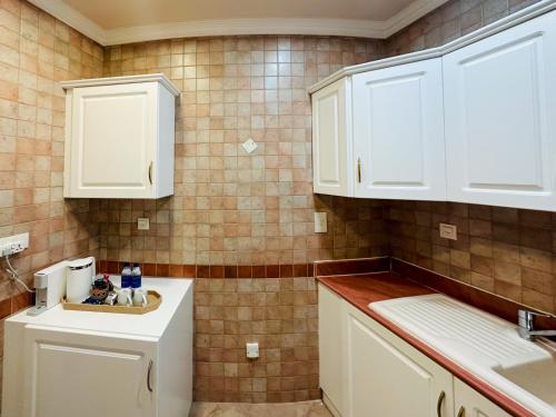a kitchen with white cabinets and a sink at I Like Al Hamra Palace - Elite Beach & Golf Resort Private Suites in Ras al Khaimah