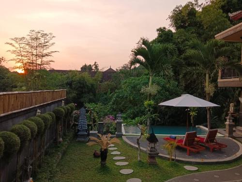 a backyard with a pool and a table and chairs at Ketut Kasta Guest House in Ubud