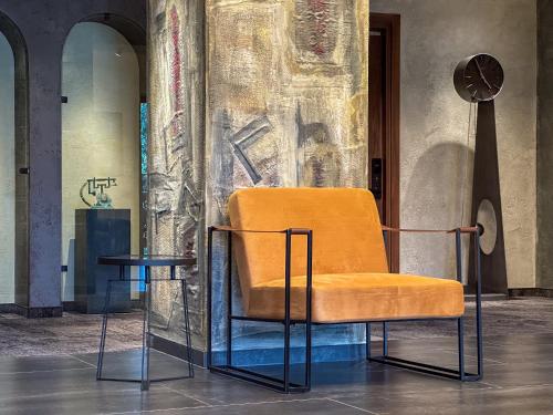 an orange chair and a table in a room at Chateau Mephis Kalaki in Akhalkʼalakʼi