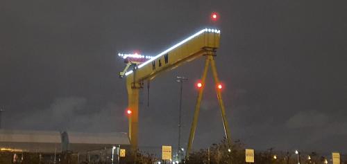 a large yellow crane with lights on it at night at Ballymena/ Belfast/ Antrim Coast/Galgorm in Ballymena