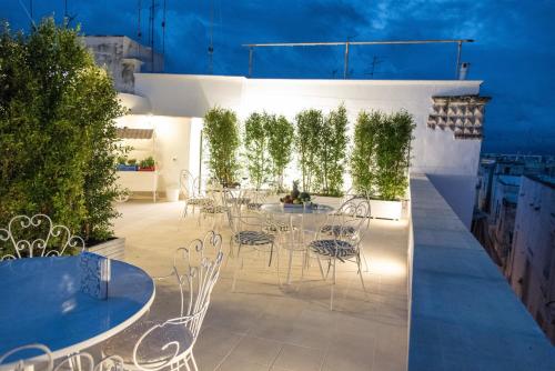 een patio met witte stoelen, tafels en planten bij Casa Rebecca in Monopoli