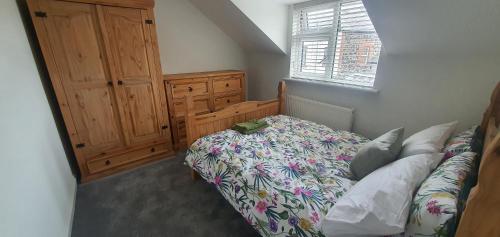 a bedroom with a bed and a wooden cabinet at Ballymena/ Belfast/ Antrim Coast/Galgorm in Ballymena