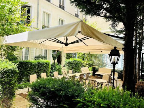 a group of tables and chairs under a white umbrella at Lord Byron in Paris