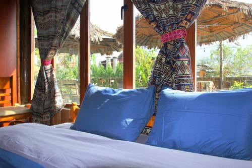a bed with blue pillows in a room with a window at Traditional Wooden house & trekking adventure in Sa Pa