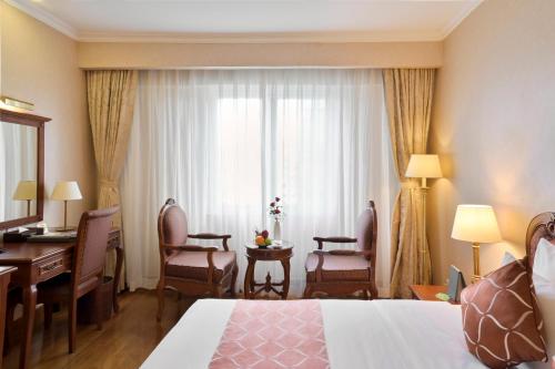 a hotel room with a bedroom with a desk and a bed at Hotel Grand Saigon in Ho Chi Minh City