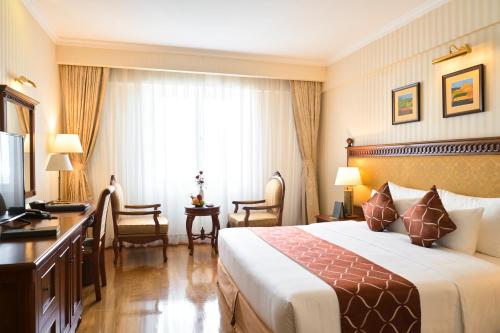 a hotel room with a bed and a desk at Hotel Grand Saigon in Ho Chi Minh City