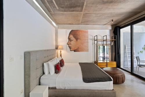 1 dormitorio con 1 cama y una gran pintura en la pared en Balissimo B11 Apartment by Hombali, en Seminyak