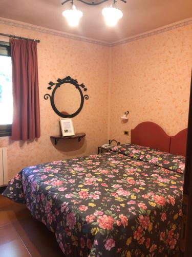 una camera da letto con un letto con un copriletto floreale e uno specchio di Hotel I Pionieri ad Abetone