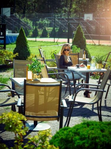 a woman sitting at a table in an outdoor restaurant at Hotel Verde in Koszalin