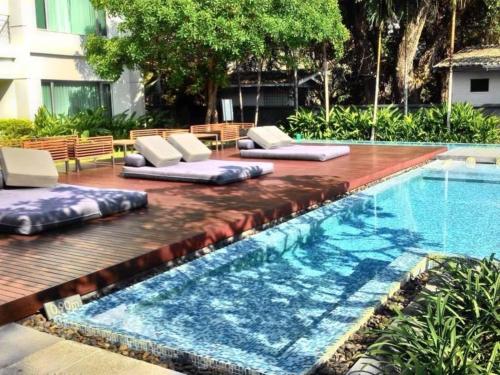 a pool with chaise lounges next to a swimming pool at Baan Sandao Unit 303 in Hua Hin