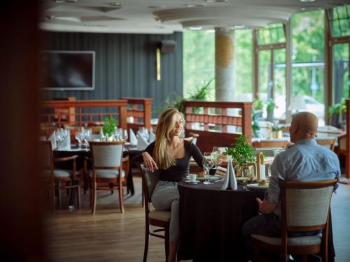 a woman sitting at a table in a restaurant at Hotel Verde in Koszalin