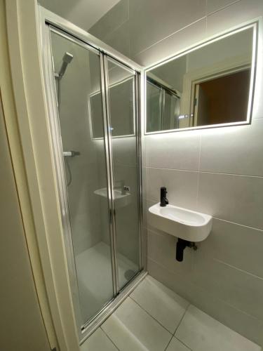 a bathroom with a glass shower and a sink at Little Wooden Hut in London