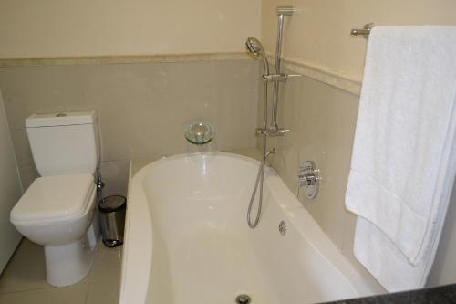 Lonehill - Standard 2 Guest Studio Suite 2 في Sandton: حوض استحمام أبيض في حمام مع مرحاض