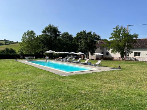 uma piscina num quintal com cadeiras e guarda-sóis em Les Cerisiers Binel à Ronsac em Aigrefeuille