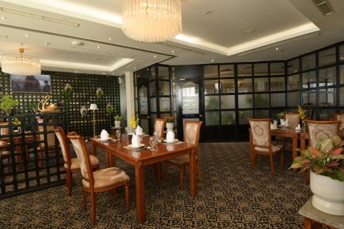 a restaurant with tables and chairs and a chandelier at Hotel Grand Saigon in Ho Chi Minh City