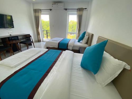 a bedroom with two beds with blue pillows and a desk at O Mary River Resort in Sihanoukville