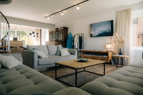 a living room with two couches and a table at Primesurf House Fehmarn in Fehmarn