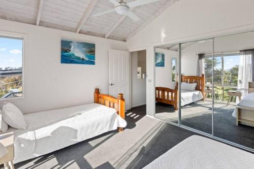 a bedroom with a bed and a glass wall at Sapphire Sunrise in Merimbula