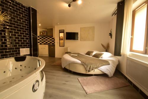 a bedroom with a large bed and a bath tub at Appartement jacuzzi Gold&Night in Verneuil d'Avre et d'Iton
