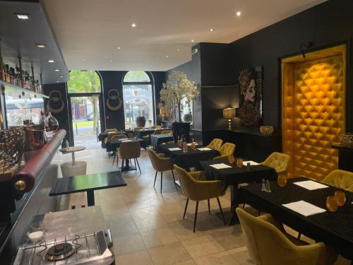 ヴァランシエンヌにあるHotel Restaurant Les Arcadesのテーブルと椅子のあるレストラン、バー