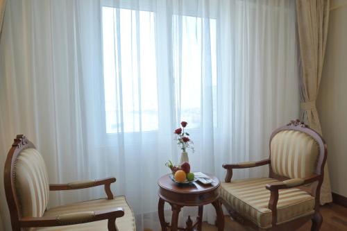 a room with two chairs and a table and a window at Hotel Grand Saigon in Ho Chi Minh City