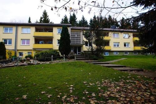 ein großes gelbes Gebäude mit einem Rasenplatz davor in der Unterkunft Ferienwohnung Mattejiet in Sankt Andreasberg