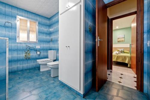 baño azul con aseo y cama en Casa ideal para familias en Amposta, en Amposta