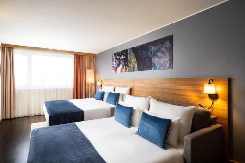 Habitación de hotel con 2 camas y sofá en Leonardo Hotel Vienna Schönbrunn, en Viena