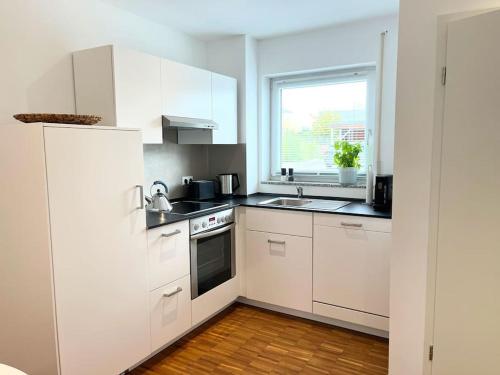 a white kitchen with white cabinets and a window at Neue, ruhige Ferienwohnung in Wolfegg