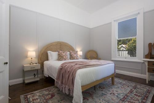 een witte slaapkamer met een bed en een raam bij ‘Endsleigh Cottage’ - Modern Luxury, Aged Charm in Cessnock