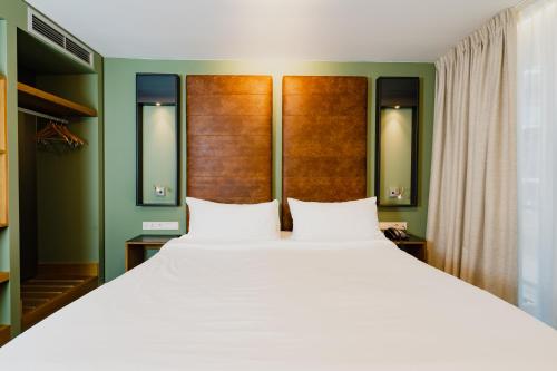 - une chambre avec un grand lit blanc et des murs verts dans l'établissement Hotel De Hallen, à Amsterdam