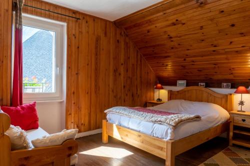 1 dormitorio con paredes de madera, 1 cama y ventana en LES PRIMEVERES en Saint-Jean-Saint-Nicolas