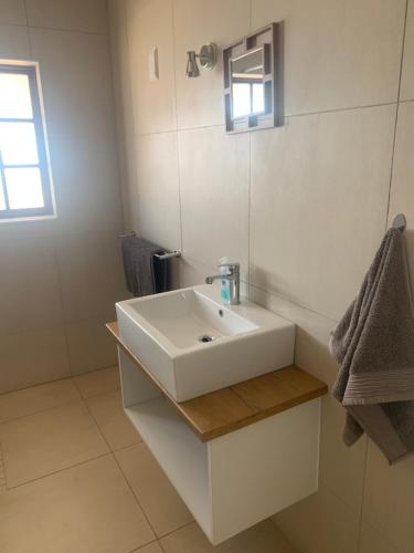 a bathroom with a white sink and a mirror at Otjibamba Lodge in Otjiwarongo