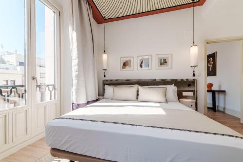 een witte slaapkamer met een groot bed en een raam bij Apartamentos Soho Boutique Hoy No Me Puedo Levantar in Madrid