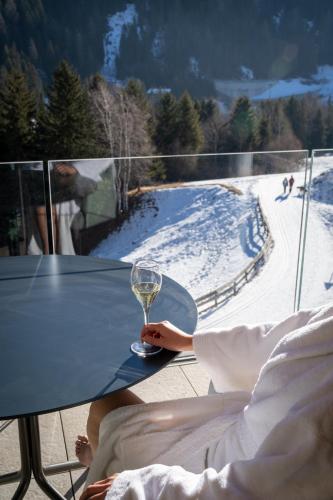 a person sitting at a table with a wine glass at Latemar - Hotel Suites Spa in Soraga