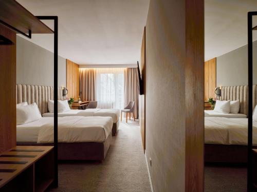 a hotel room with two beds and a desk at Hotel Verde in Koszalin