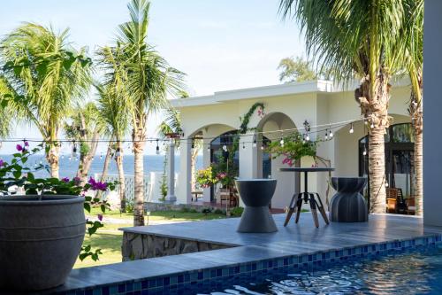 a villa with a swimming pool and palm trees at La'mer Villa Mũi Né in Phan Thiet