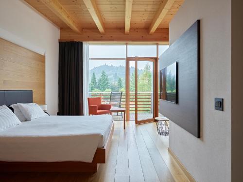a hotel room with a bed and a balcony at Corona Dolomites Hotel in Andalo