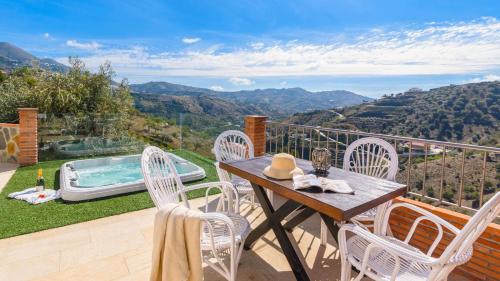 a patio with a table and chairs and a hot tub at Casa El Refugio de Árchez by Ruralidays in Árchez