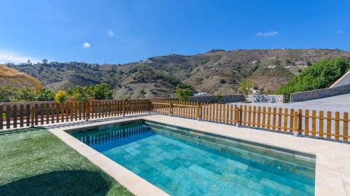 a swimming pool with a fence and mountains in the background at Casa El Refugio de Árchez by Ruralidays in Árchez