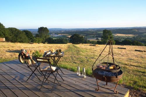 a table and two chairs and a fire pit on a deck at Tilbury Shepherd Huts with Hot Tubs Plus Holiday Cottages in West Bagborough