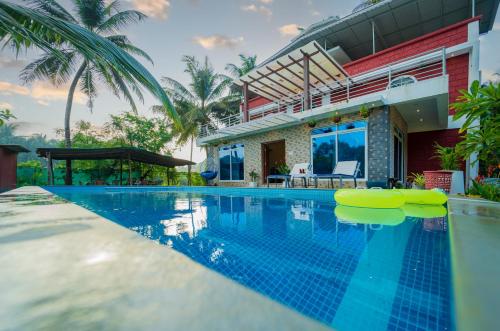 a swimming pool in front of a house at Spicy Mango Villa Elegano - Luxurious Villa Near Nagaon Beach, Alibag in Nagaon