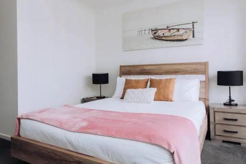 a bedroom with a large bed and two lamps at Beachside Townhouse in Mornington