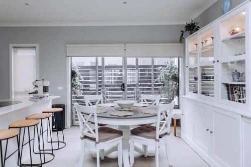 a white dining room with a white table and chairs at Beachside Townhouse in Mornington