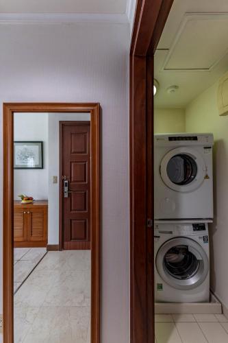 a laundry room with a washer and dryer next to a door at Garden View Court Suites Ho Chi Minh City in Ho Chi Minh City